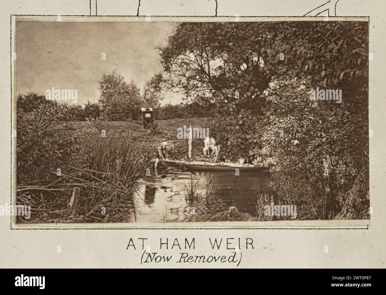 At Ham Weir (Now Removed). Henry W. Taunt, photographer (British, 1842 - 1922) about 1886 One of three tipped-in photographs illustrating a printed map of Castle Eaton, Kempsford, and the surrounding area along the River Thames. The photograph shows a view of Henry Taunt crouched on the bank of the river at a small weir, or dam. Taunt holds the bow of a canoe floating on the water as a second man crouches near him on the riverbank. Taunt's photographic tent stands in a field behind the men. (Recto, mount) lower center, below image, printed in black ink: 'AT HAM WEIR / (Now Removed) [italicized Stock Photo