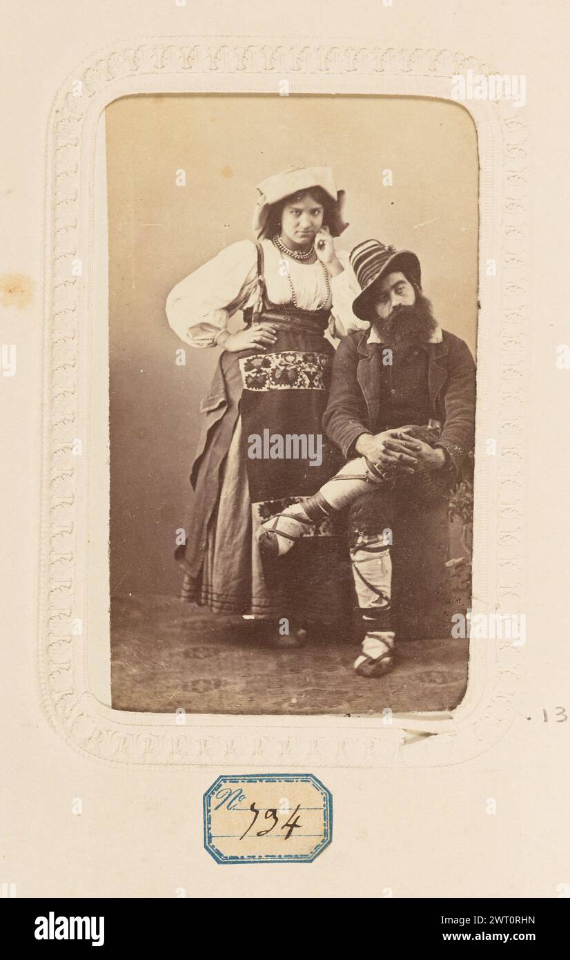 Costumes Italiens. Unknown, photographer about 1860–1880 A portrait of a man and woman dressed in traditional Italian clothing. The woman is wearing a dress with wide sleeves and an embroidered apron. She has a cloth hat on her head that hangs down in the back. The man is seated with one leg crossed over the other. He is wearing a striped hat and has a thick beard. (Recto, mount) lower center, black ink: 'Costumes Italiens'; lower center, black ink: 'Costumes Italiens'; (Recto, album page) lower center, below image, black ink on blue label: 'No [in blue text] 134'; Stock Photo