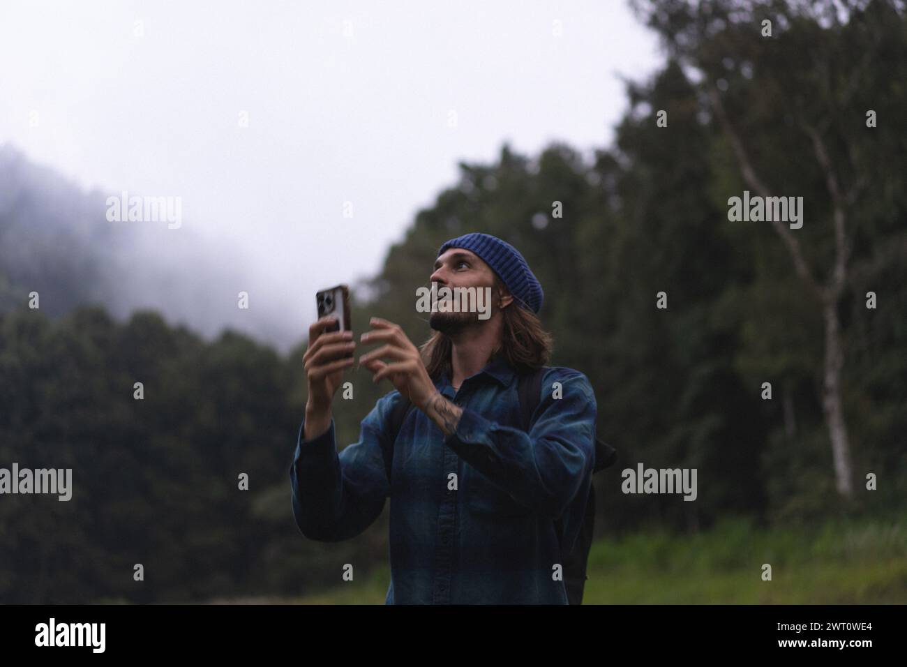 A man traveler in the rainforest takes pictures on his phone. Stock Photo