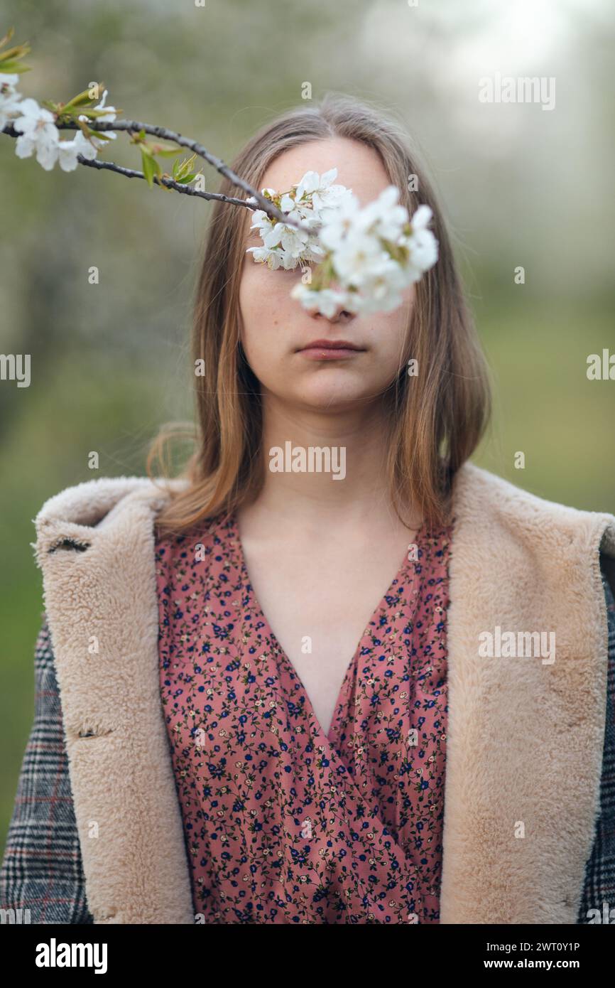 a flowering branch covers the girl's eyes Stock Photo