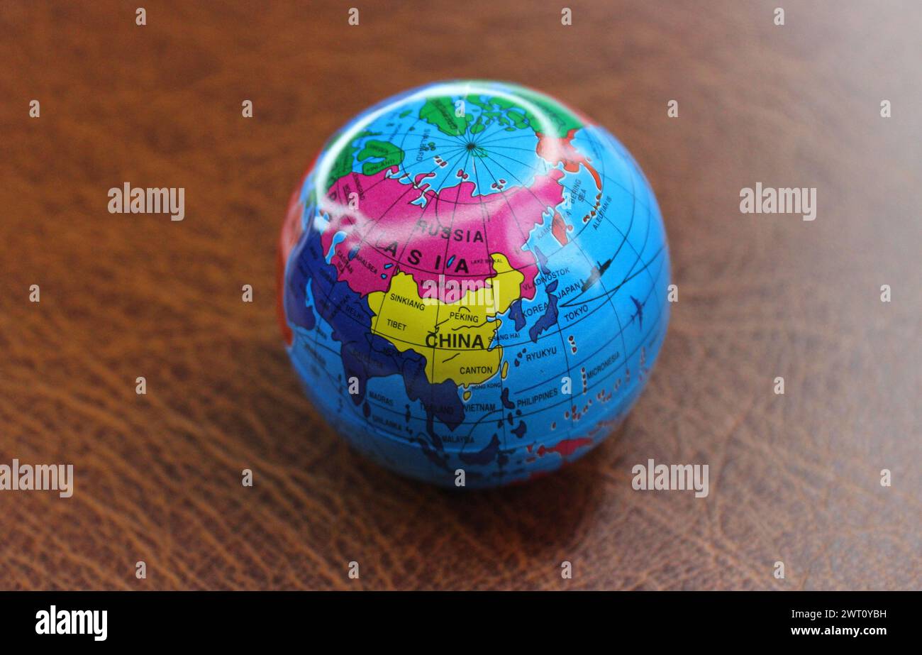 Small Round Globe With A Visible Image Of The Asian Countries Lying On Leather Surface Stock Photo