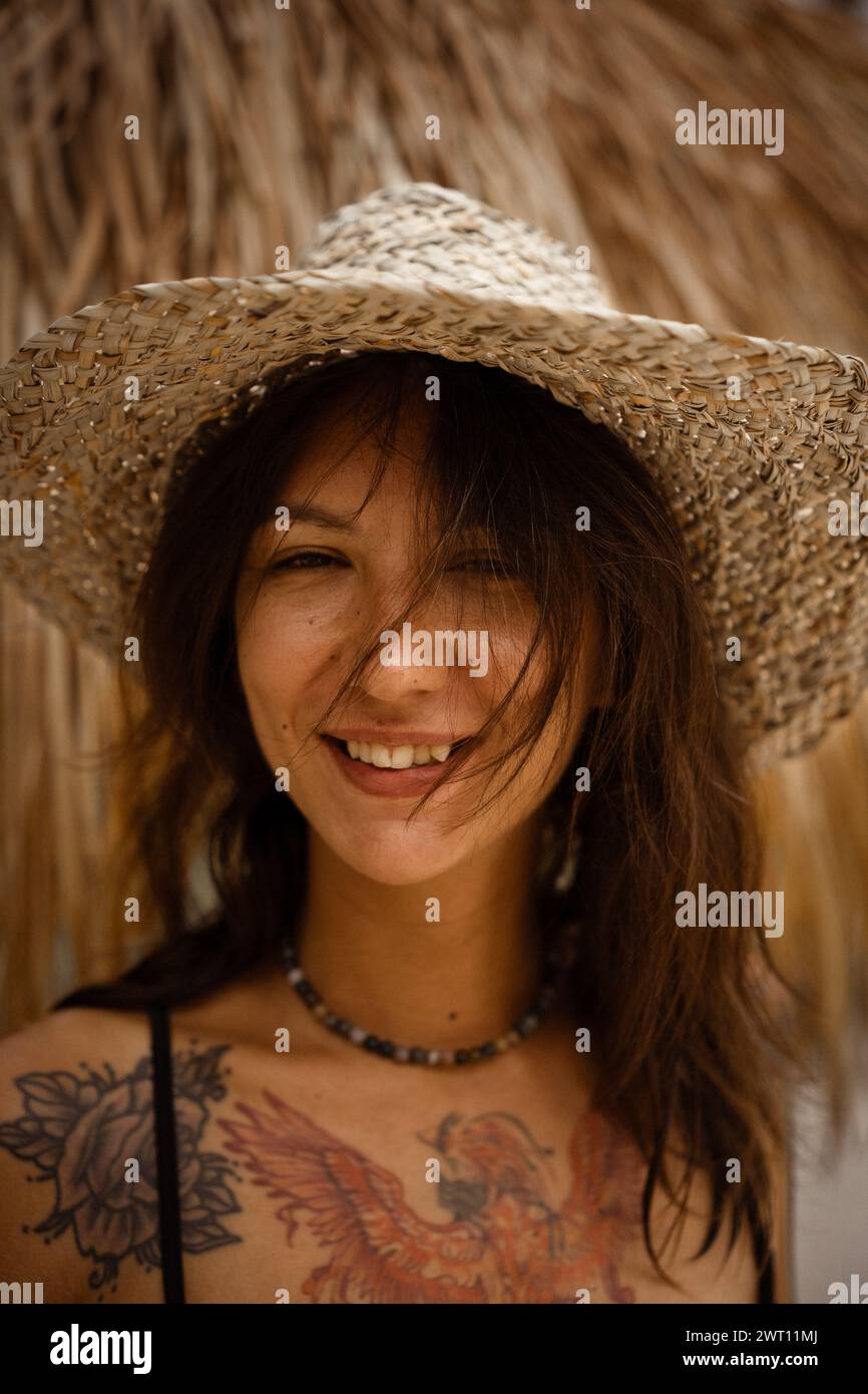 Portrait of a happy woman on the beach in a swimsuit and straw hat ...