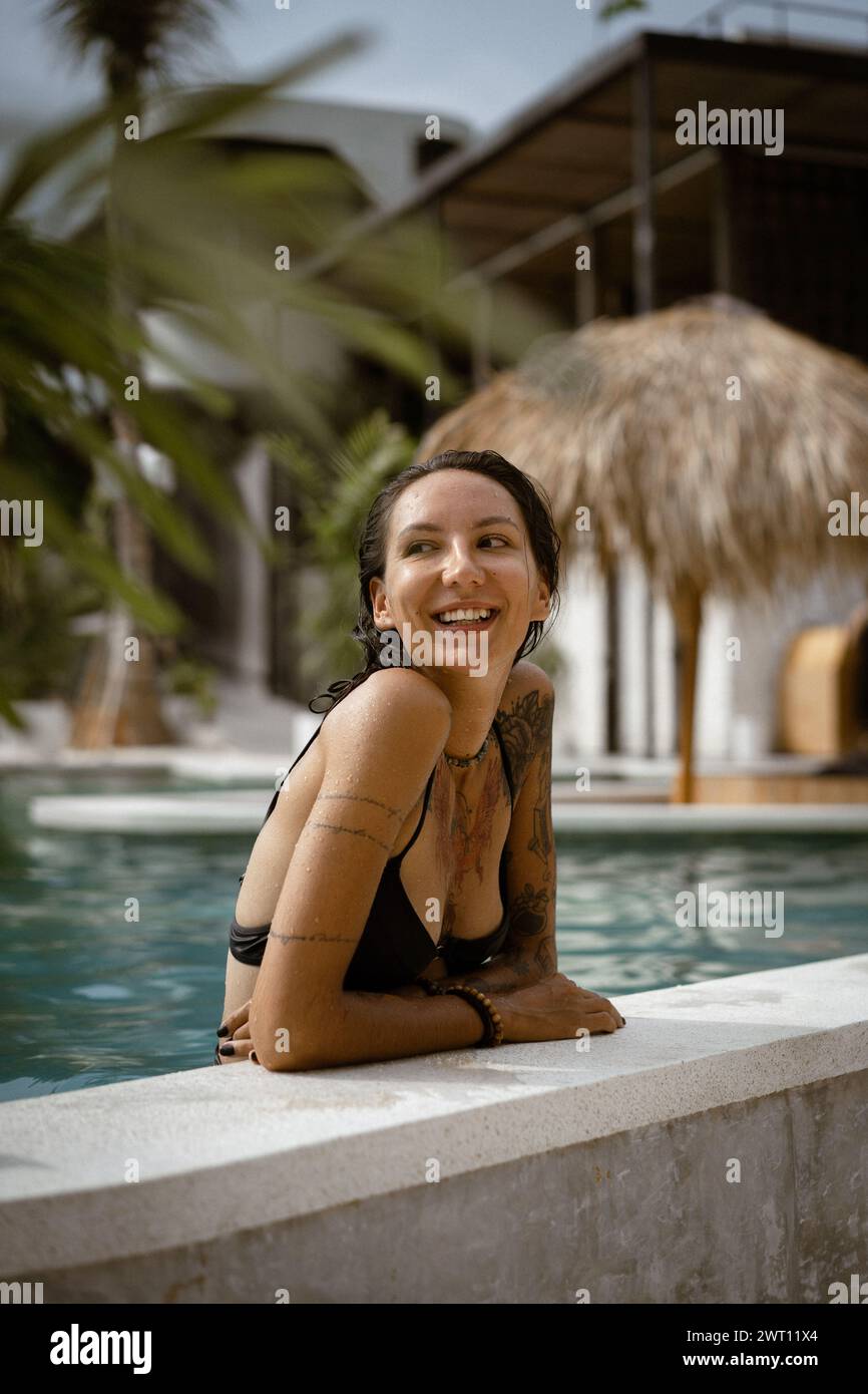 Young tattooed woman relaxing in the swimming pool. Stock Photo