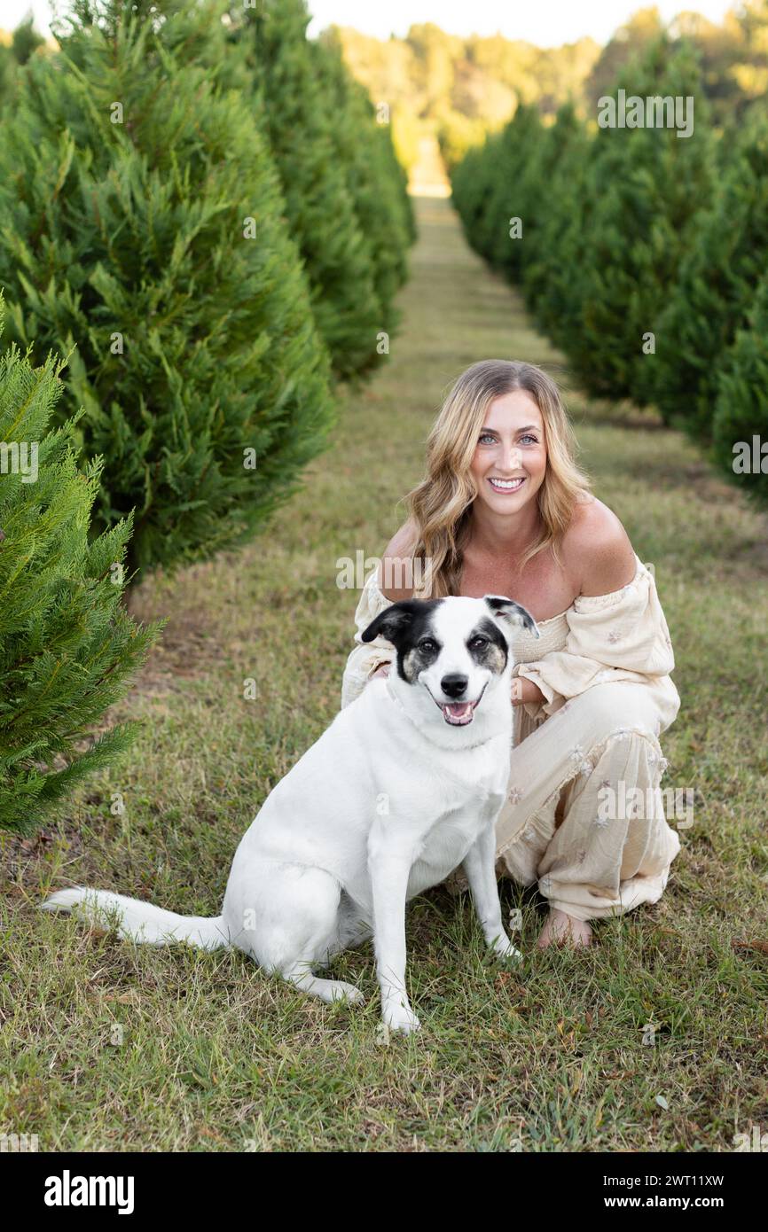 Cheerful moment at a Christmas tree farm with a woman anddog Stock Photo