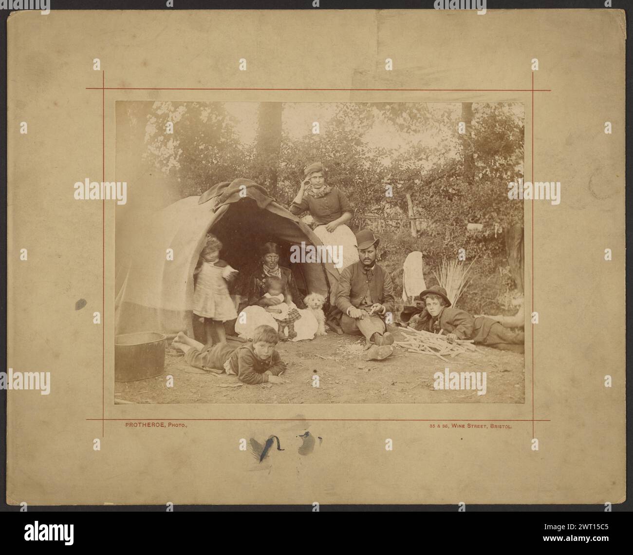 Romany family gathered around tent. T. Protheroe, photographer (British, active 1850s - 1890s) about 1855–1865 A Romany family gathered around a 'bender' tent. A woman with two young girls are in the tent, a man and two boys on the ground outside. Another woman rests her arm along the top of the tent. (Recto, mount) lower left, imprint in red ink: 'Protheroe, Photo.,'; Lower right, imprint in red ink: '35 and 37, Wine Street, Bristol'; Stock Photo