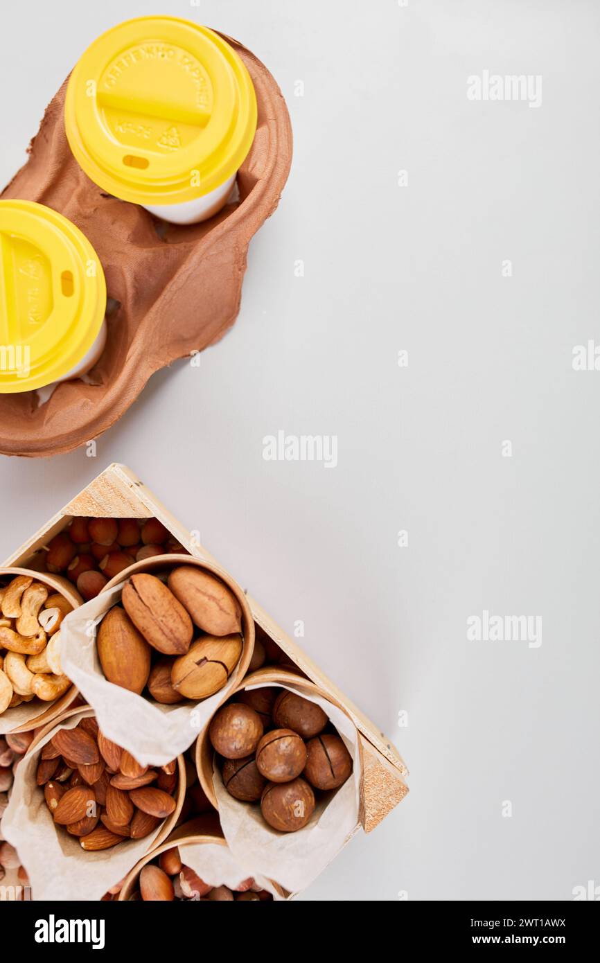 Two Takeaway Coffee Cups and a Variety of Nuts on a Bright Background. Stock Photo