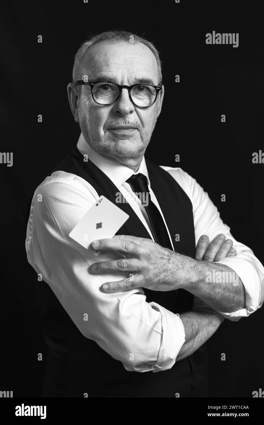 A magician manipulates playing cards to perform a magic trick. Dressed ...