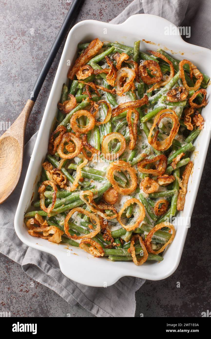 Green bean casserole is an American baked dish consisting of green beans, cream of mushroom soup, and french fried onions on the baking dish on the ta Stock Photo