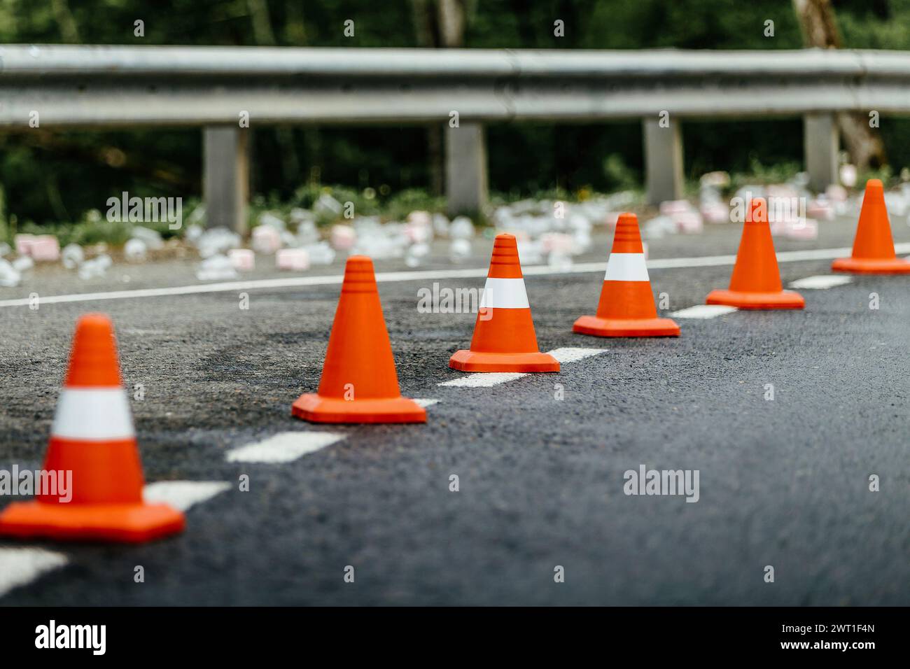 six orange traffic cones standing in row on mountain road Stock Photo