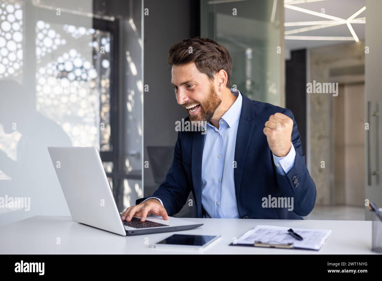 Happy young businessman sitting in the office at the table and looking ...