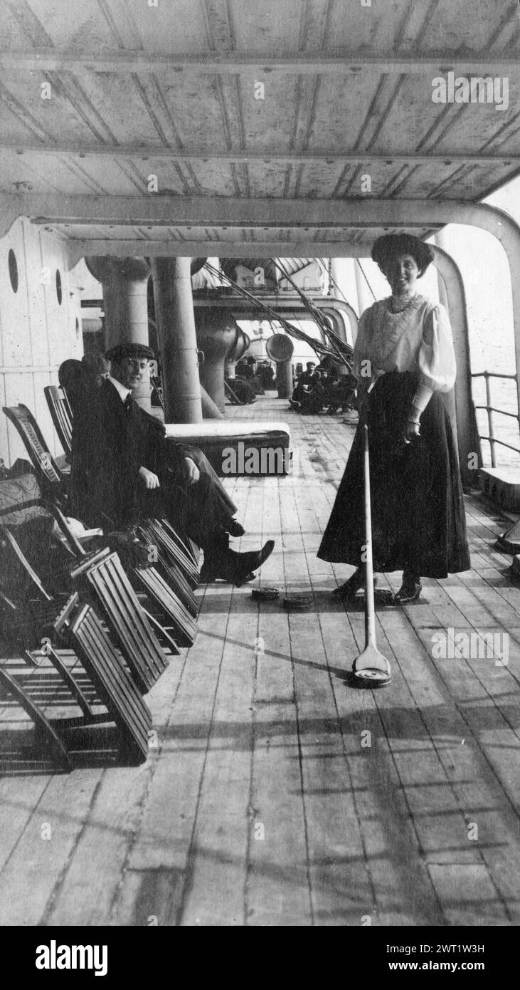 Vintage  Photography. Couple having fun playing shuffleboard on the deck of the steamship “Mongolian” , Ontario, Canada  historical photo by Hugh A. Peck Stock Photo