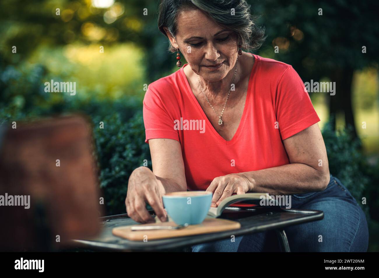 Senior woman reading book in outdoor coffee shop Stock Photo - Alamy