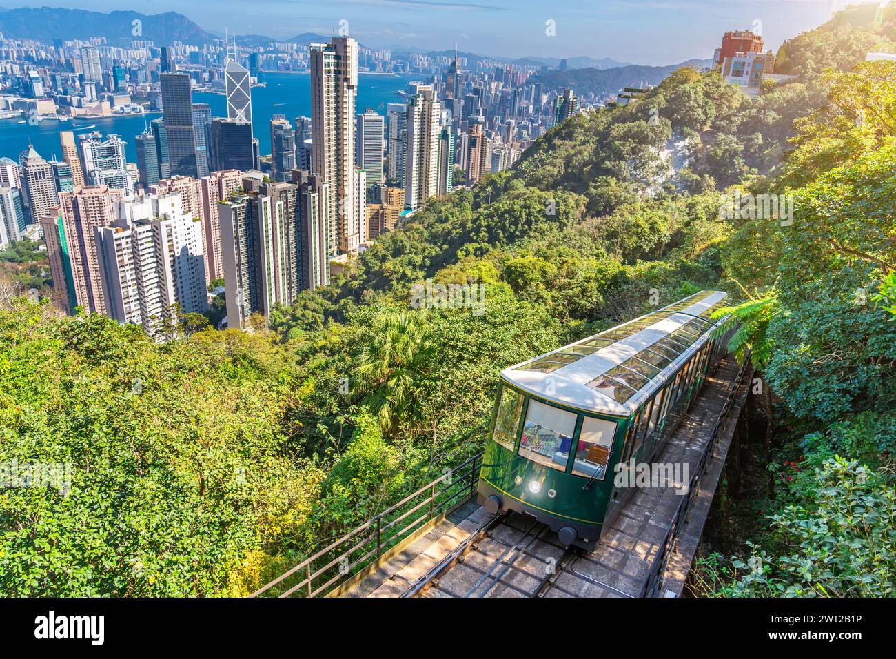 The famous green tram on the slope of Victoria Peak in Hong Kong passes, lifting visitors to the observation deck at the top. Stock Photo