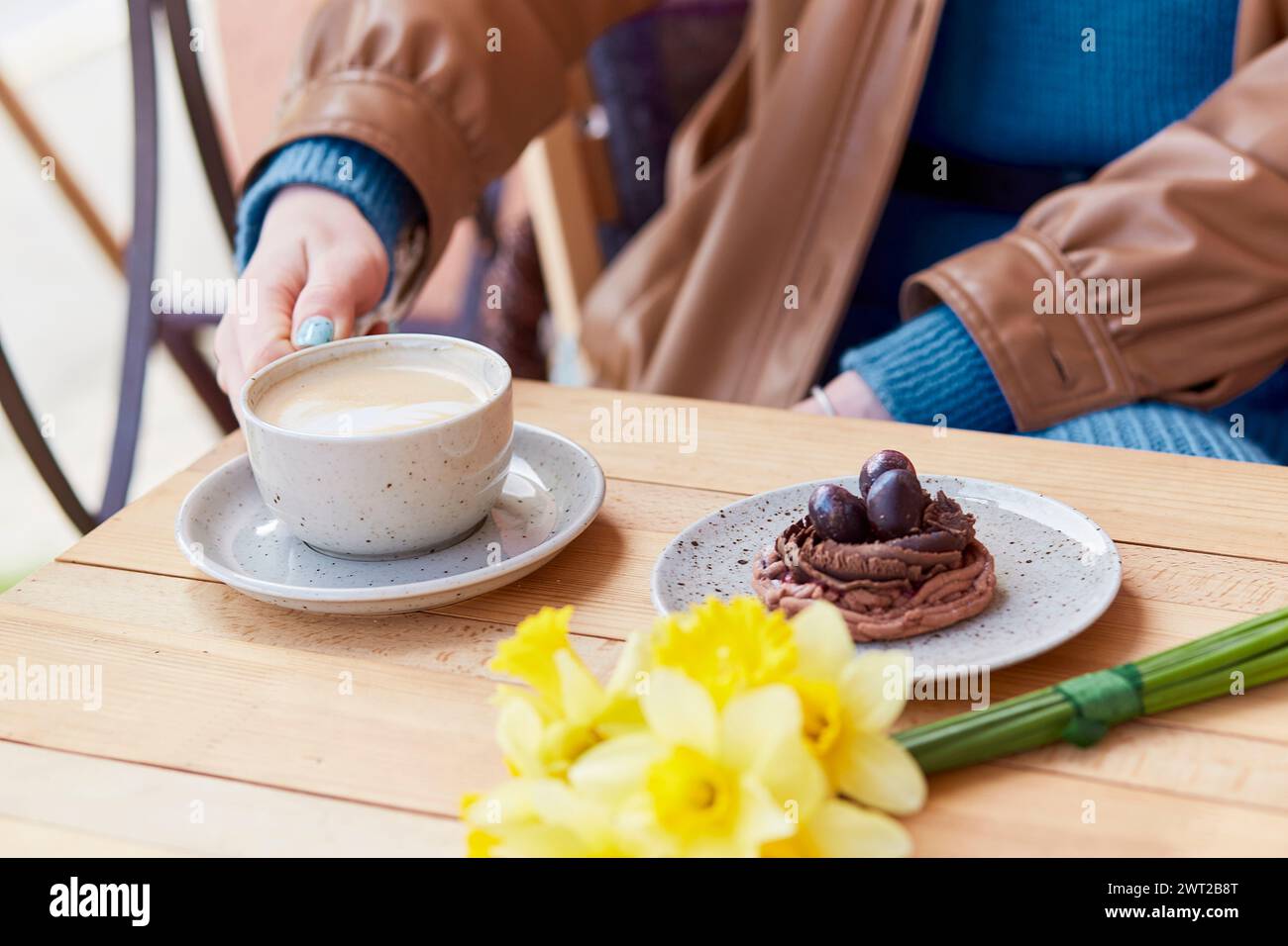 Sweet and floral - enjoying a cafe moment with cappucino, dessert and daffodils. Stock Photo