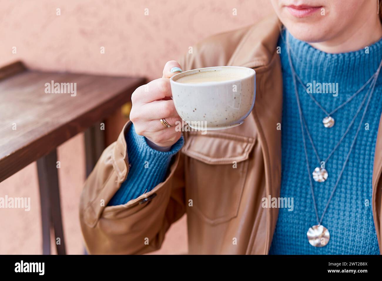 Close up woman with blue manicure holds a coffee cup with cappuccino. Stock Photo