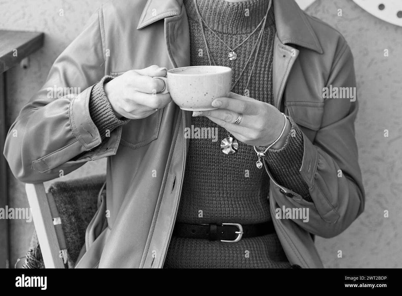 Close up woman with blue manicure holds a coffee cup with cappuccino. Black and white background. Stock Photo