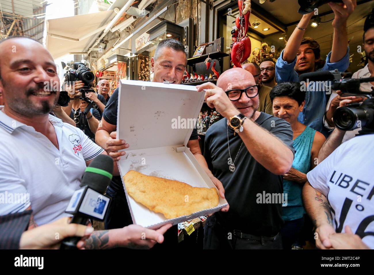 The Dolce & Gabbana stylists walking around San Gregorio Armeno in Naples with a fried pizza, a pizza chef's gift Stock Photo