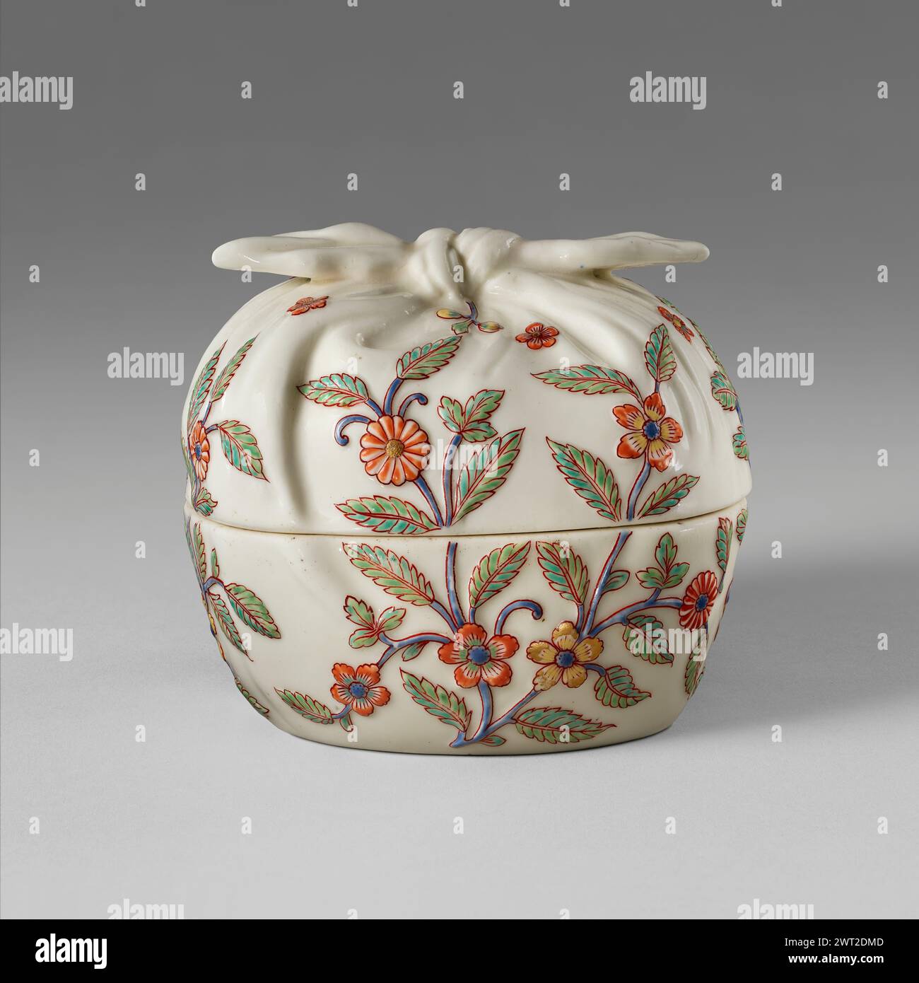 Box. Saint-Cloud Porcelain Manufactory, manufacturer (French, active by 1693 - 1766) 1730–1740 The small box is imaginatively conceived to look like an object that has been wrapped by a piece of fabric gathered at the top and tied in a double knot. The ornament of stylized leafy blooming branches delicately colored in blue, green, yellow, and orange enamel is slightly raised echoing the effect of embroidery. It is the only known piece of this shape and is a particularly sophisticated example of polychrome ware made at Saint-Cloud. The floral pattern extending over the joint between the base an Stock Photo