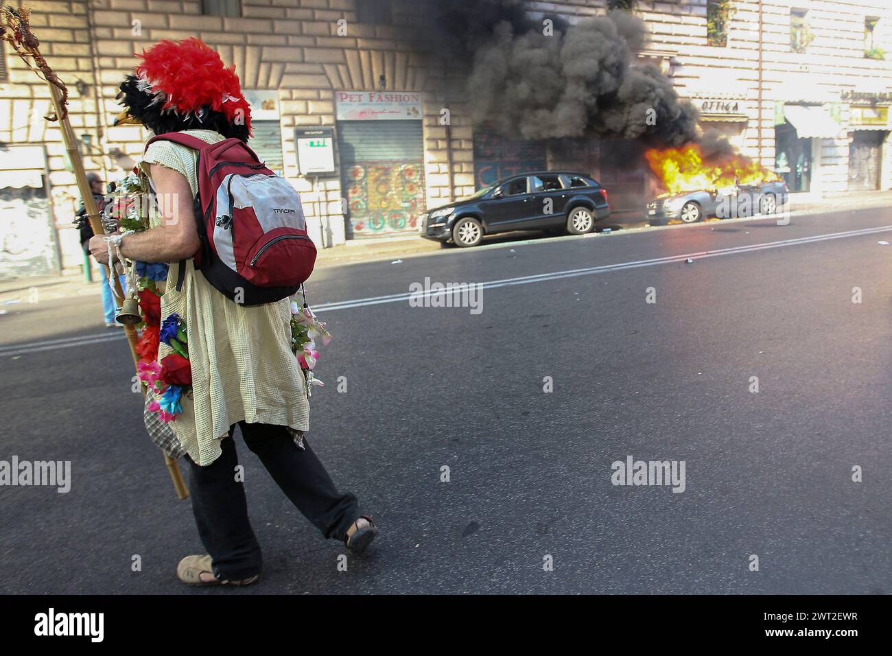 A protester looks at a car burned by the Black Bloc during a demonstration in Rome Stock Photo