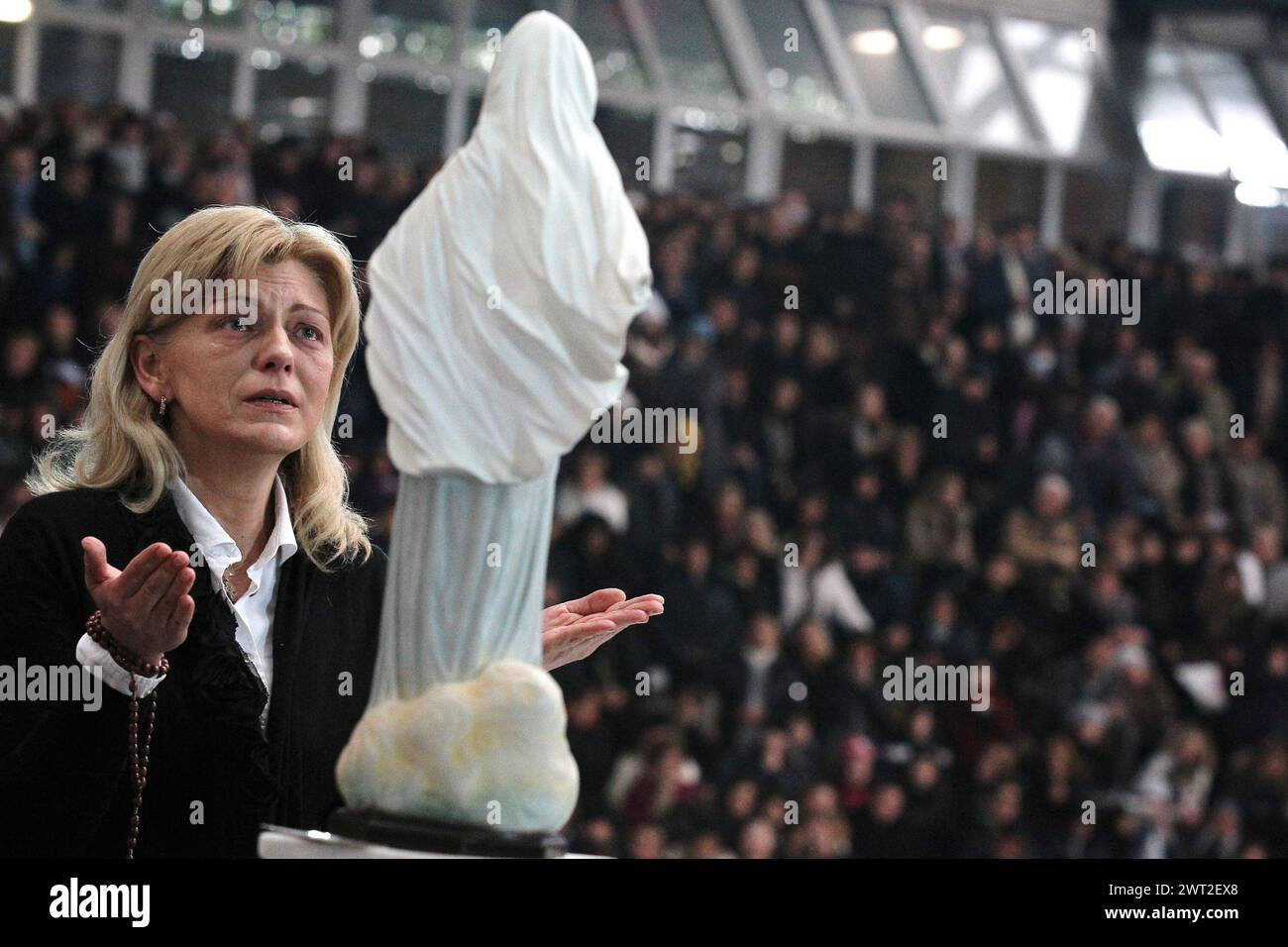 The clairvoyant Mirjiana Dragicevic, prays in front of a statue of Our Lady of Medjugorje, during a religious event in Naples Stock Photo