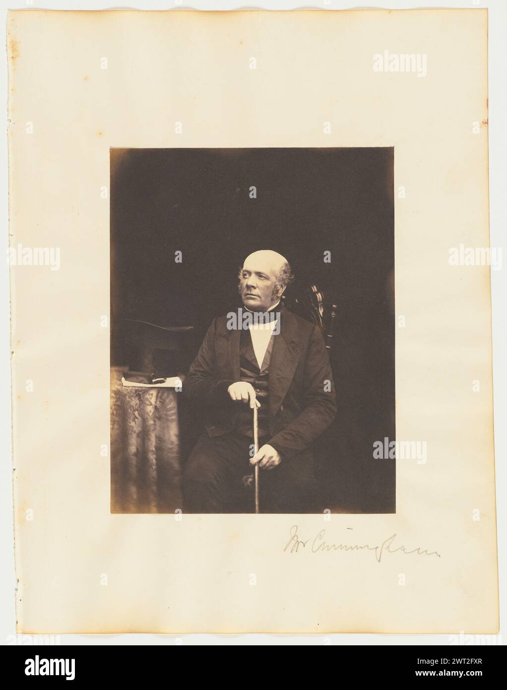 Mr. Cunningham. Probably Thomas Rodger, photographer (Scottish, 1832 - 1883) about 1850–1859 A portrait of a seated man holding a cane. A top hat is resting on a small table beside him. (Recto, mount) lower right, pencil: 'Mr Cunningham'; (Verso, mount) upper right, pencil: '31'; Stock Photo