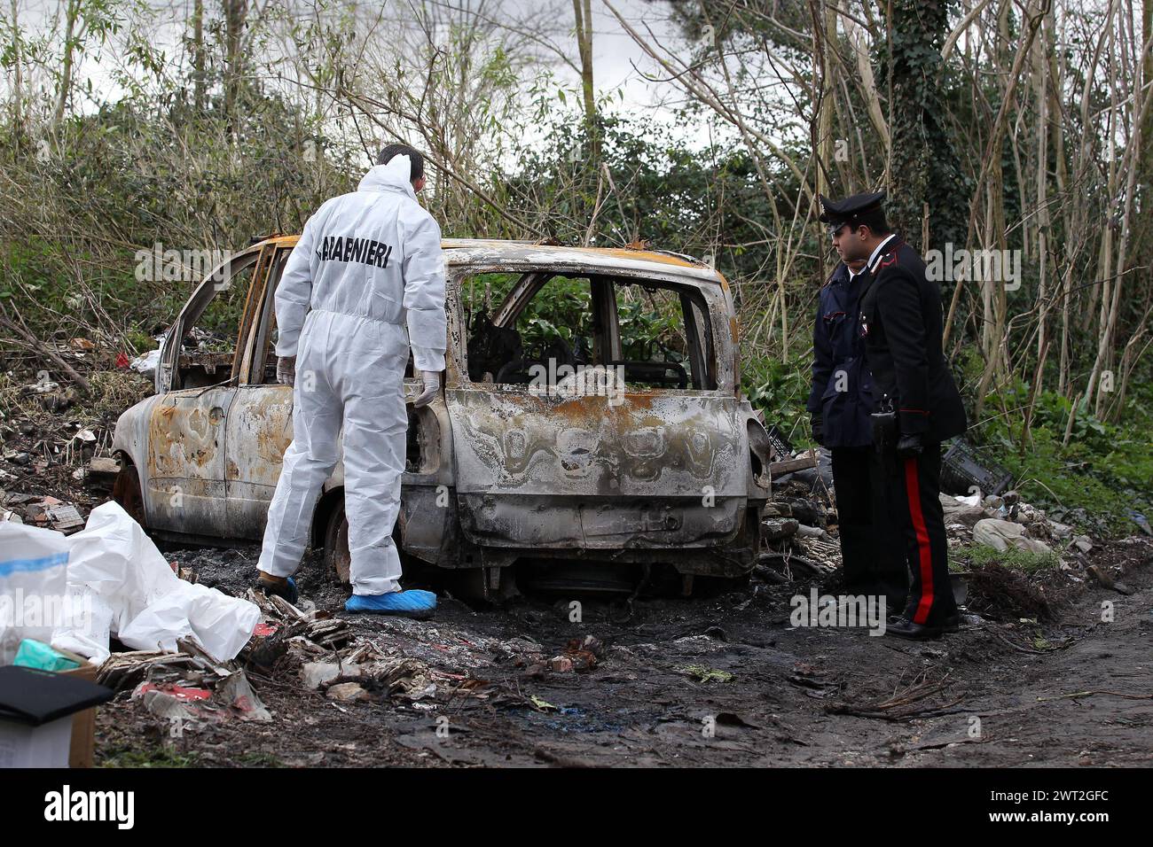 A charred corpse in a car burned on a country path. The scientific police and the Carabinieri are close to the car Stock Photo