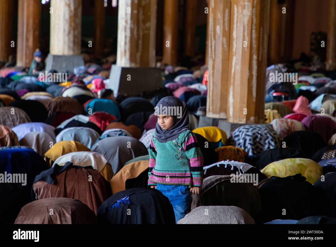 Srinagar, India. 15th Mar, 2024. A Kashmiri Muslim girl looks on as women offer prayers inside the Jamia Masjid or Grand Mosque on the first Friday of Ramadan in Srinagar. Muslims around the world marking the holy month of Ramadan by praying during the night time and abstaining from eating and drinking during the period between sunrise and sunset. Ramadan is the ninth month in the Islamic calendar and it is believed that the Quran's first verse was revealed during its last 10 nights. (Photo by Faisal Bashir/SOPA Images/Sipa USA) Credit: Sipa USA/Alamy Live News Stock Photo