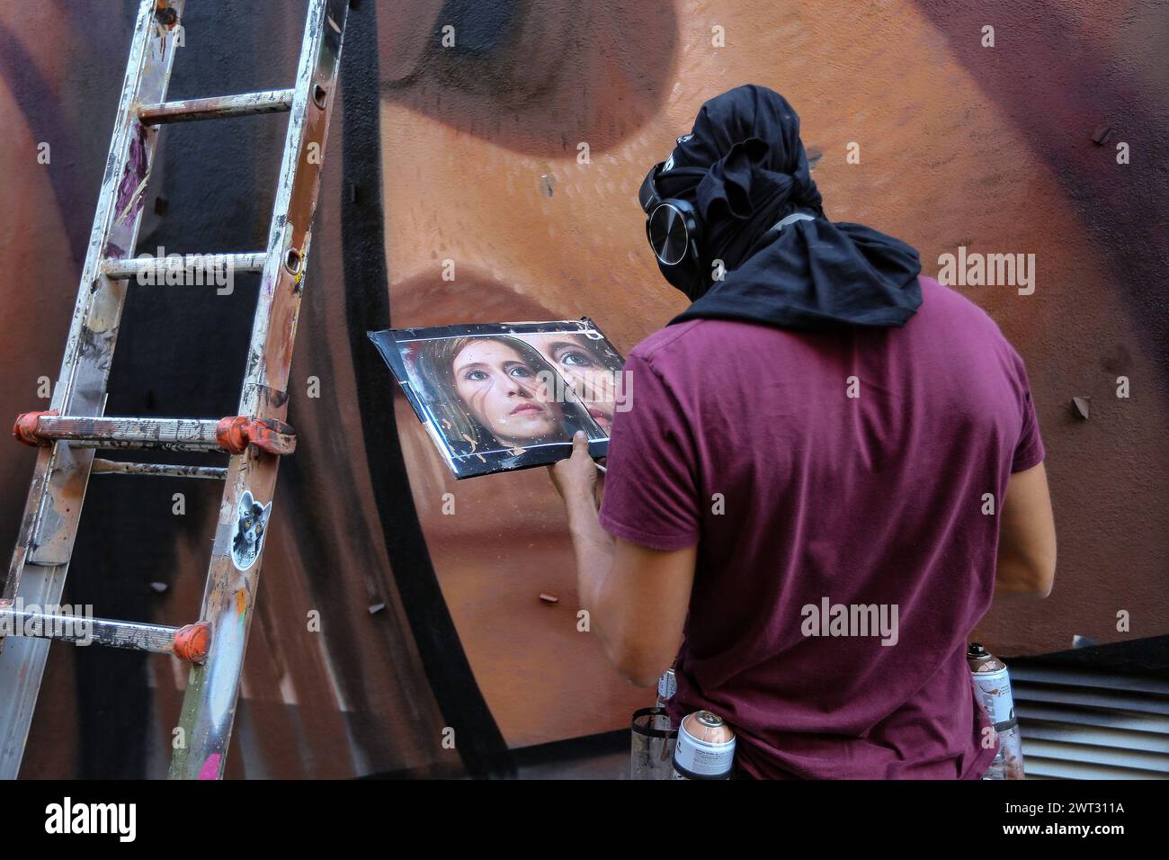 The street artist Jorit Agoch at work on a giant murales of Ilaria Cucchi, sister of Stefano Cucchi, who fought for justice after the death of his bro Stock Photo