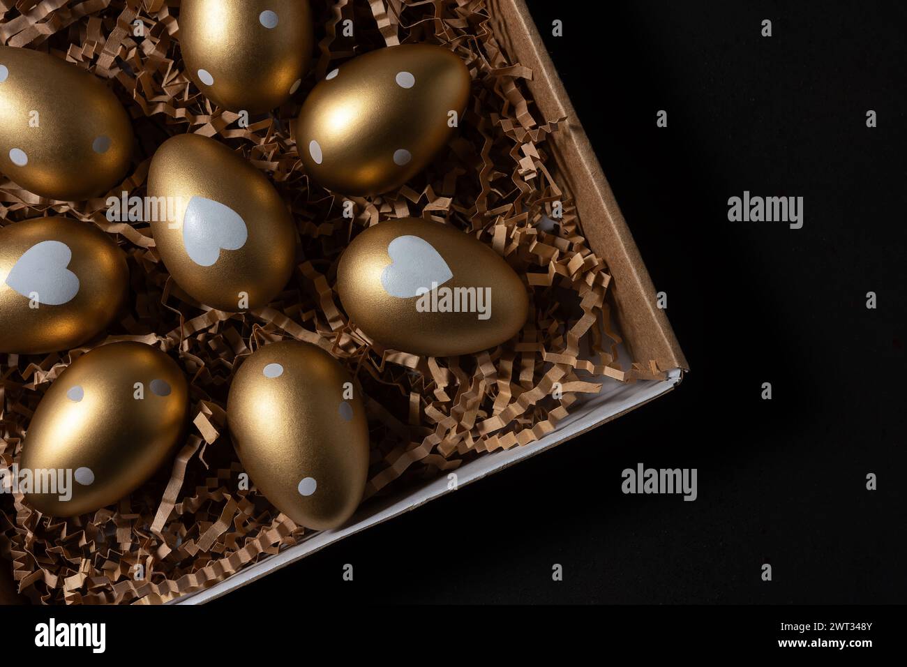 Gold eggs in paper box on black background. Stock Photo
