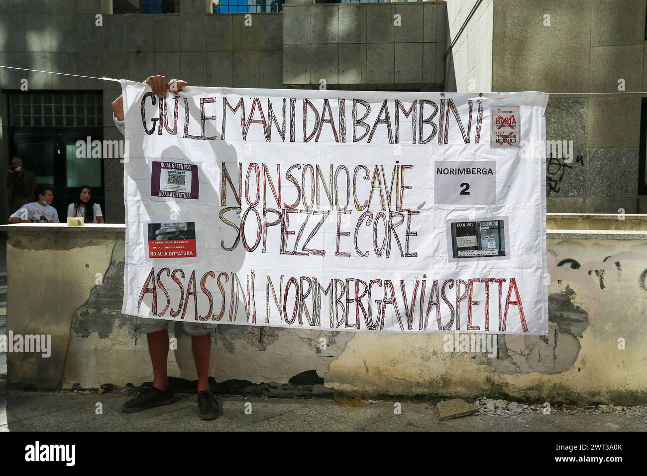 A man attaches a banner, in front of the seat of the regional council of Campania, against the entry into force of the Green Pass, the precautionary m Stock Photo