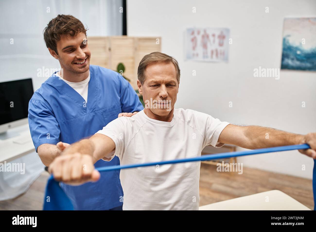 joyous attractive doctor in blue robe helping his mature patient to use ...