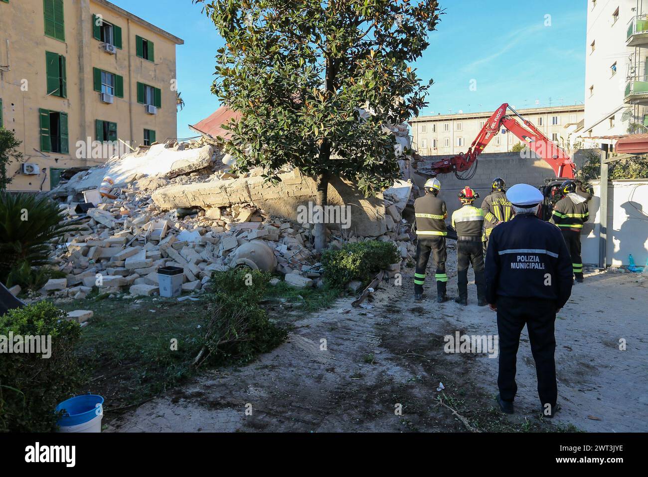 Firefighters watch an excavator as it removes the rubble of the completely collapsed building in San Felice Cancello, in the province of Caserta, foll Stock Photo