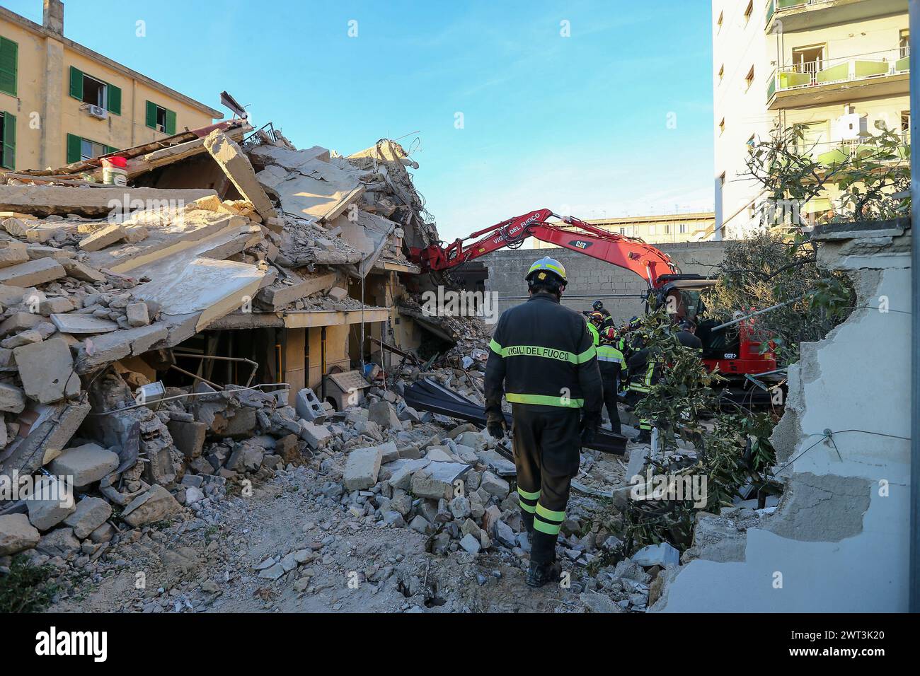 Firefighters watch an excavator as it removes the rubble of the completely collapsed building in San Felice Cancello, in the province of Caserta, foll Stock Photo