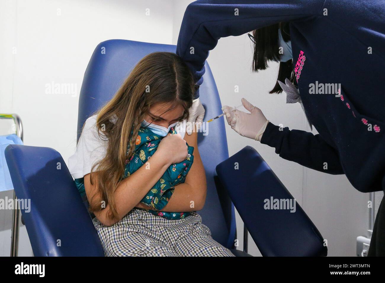 A little girl getting vaccinated, on the first day of vaccination in Italy for children aged 5 to 11, inside a room of the vaccination center set up t Stock Photo