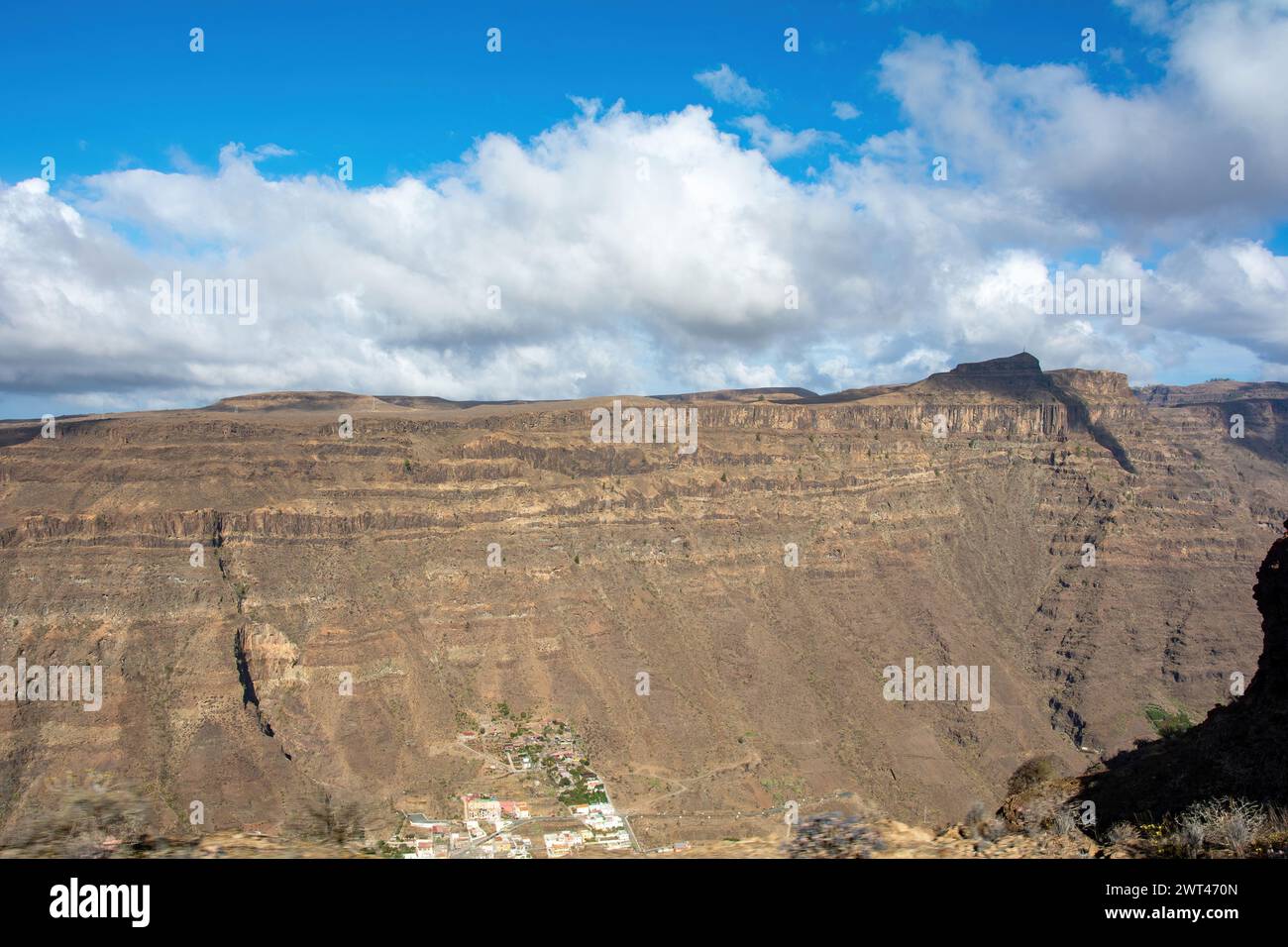 Mountains with a small village in the valley on the Canary Island of Gran Canaria in Spain, with blue sky and clouds Stock Photo