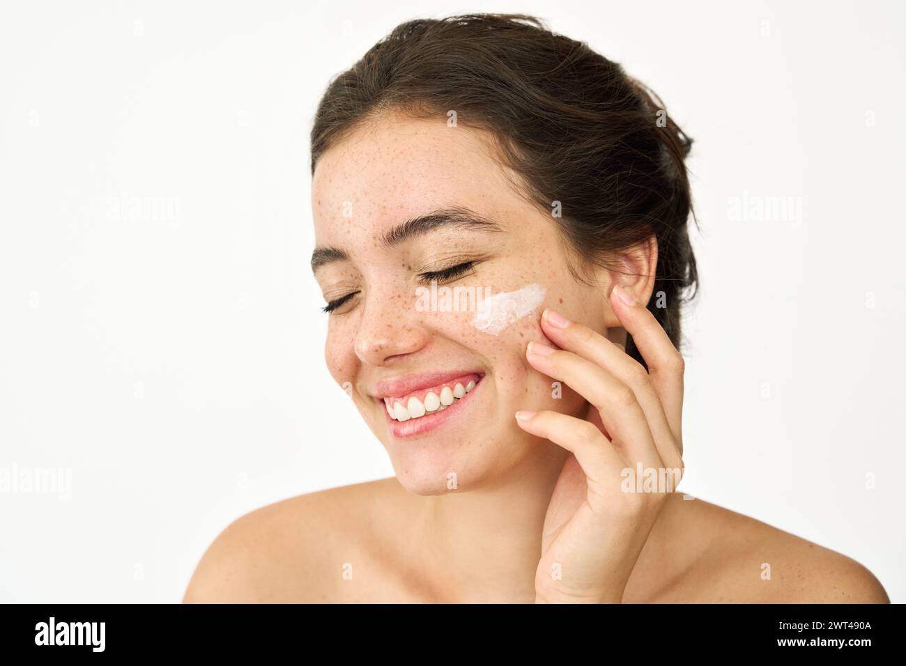 Young Latin woman applying face cream isolated on white background, skincare. Stock Photo