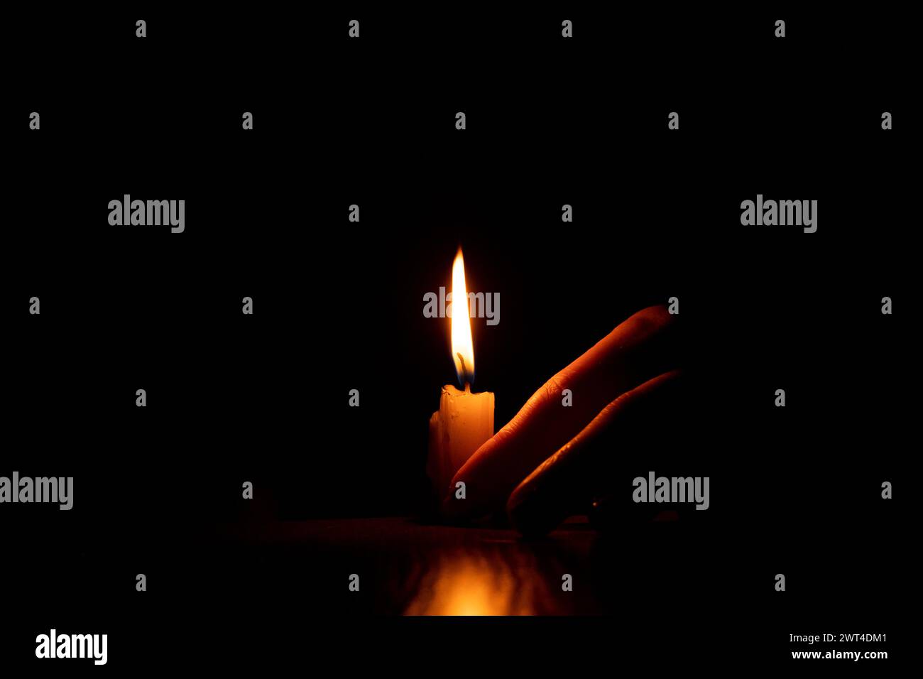 Women's hands near a candle flame in the dark, faith and religion, praying Stock Photo