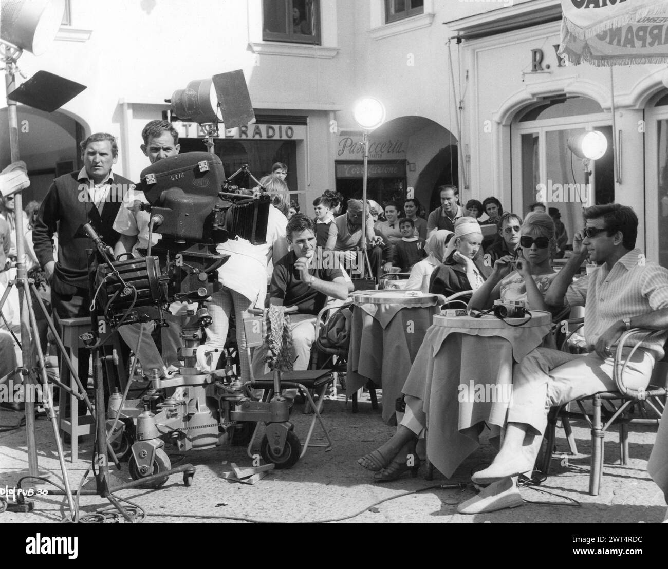 A candid photo of British Actress JULIE CHRISTIE and ROLAND CURRAM with the camera crew filming a scene in Capri for DARLING 1965  Director JOHN SCHLESINGER  Screenplay FREDERIC RAPHAEL Costume Design JULIE HARRIS Music JOHN DANKWORTH Vic-Appia Films / Anglo Amalgamated Stock Photo