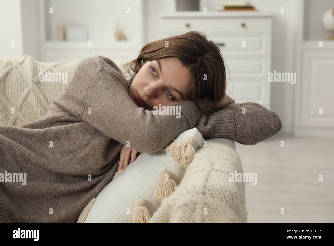 Sad young woman lying on sofa at home Stock Photo - Alamy