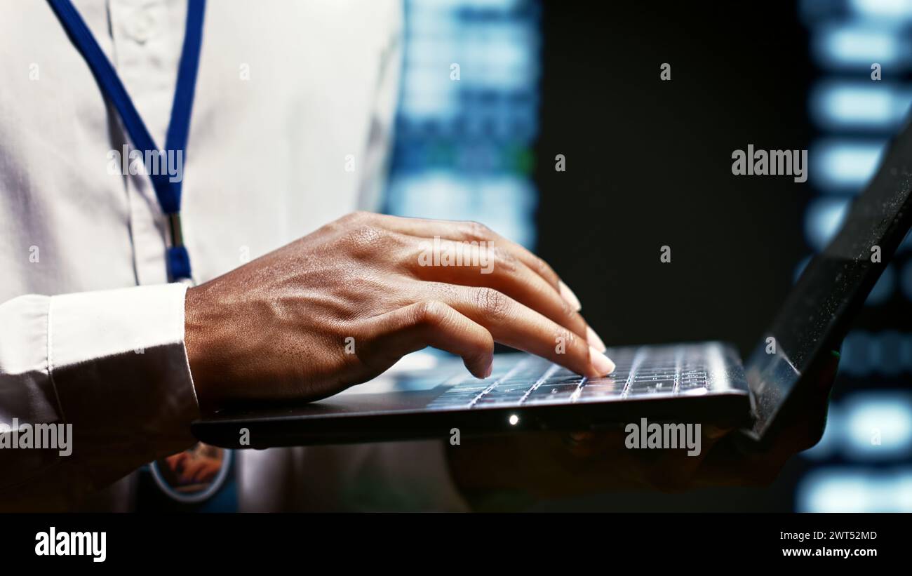 IT developer using laptop to examine server mainframes providing vast computing resources and storage, enabling artificial intelligence to process massive datasets for training and inference, close up Stock Photo