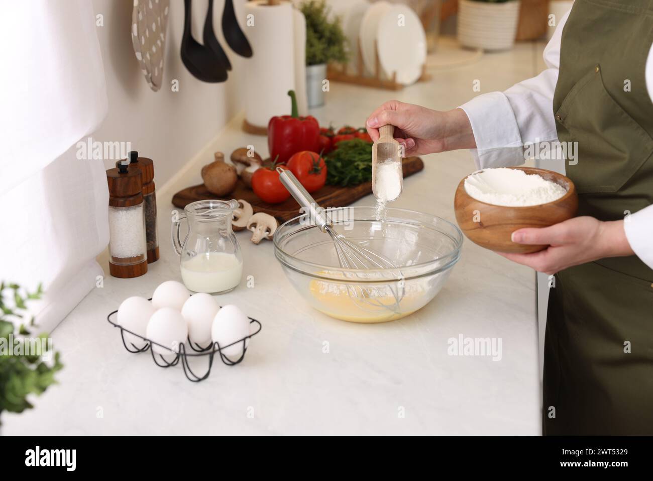 Woman adding flour into bowl at light table, closeup Stock Photo - Alamy