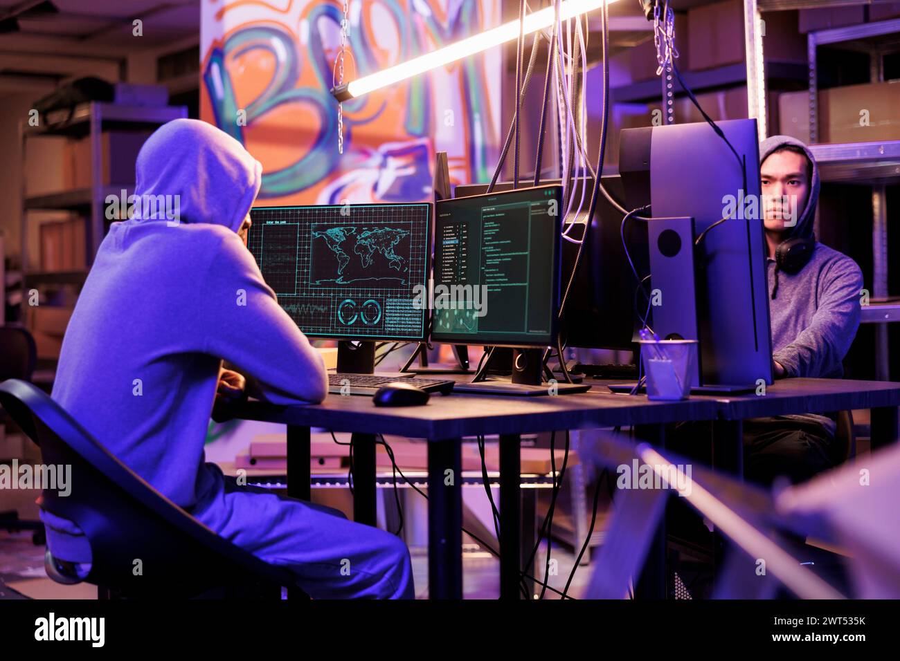 Hackers planning malware attack on government computer network system and coding ransomware. Criminals programming malicious software to hack database server in abandoned warehouse Stock Photo