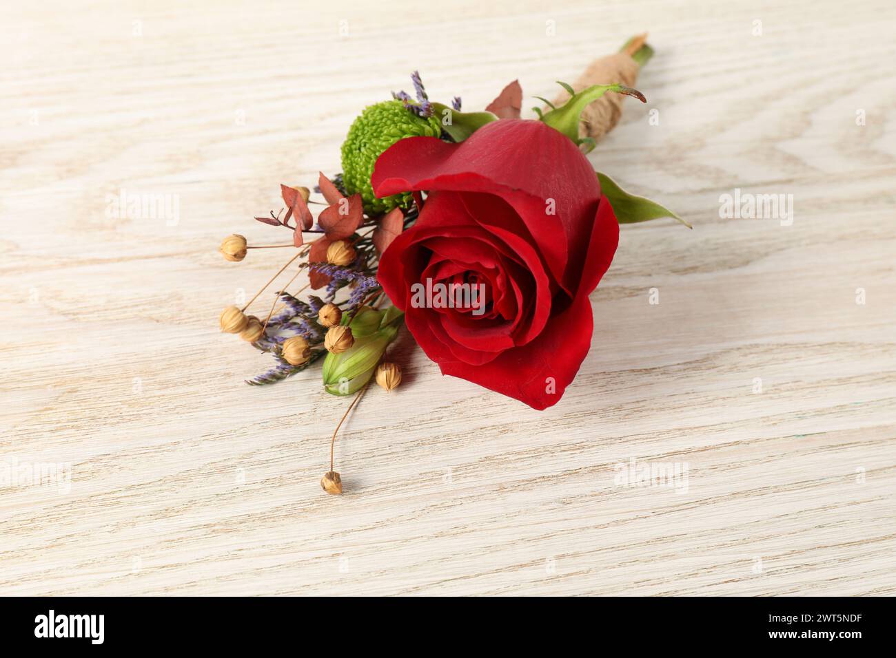 Stylish boutonniere with red rose on light wooden table, closeup Stock Photo