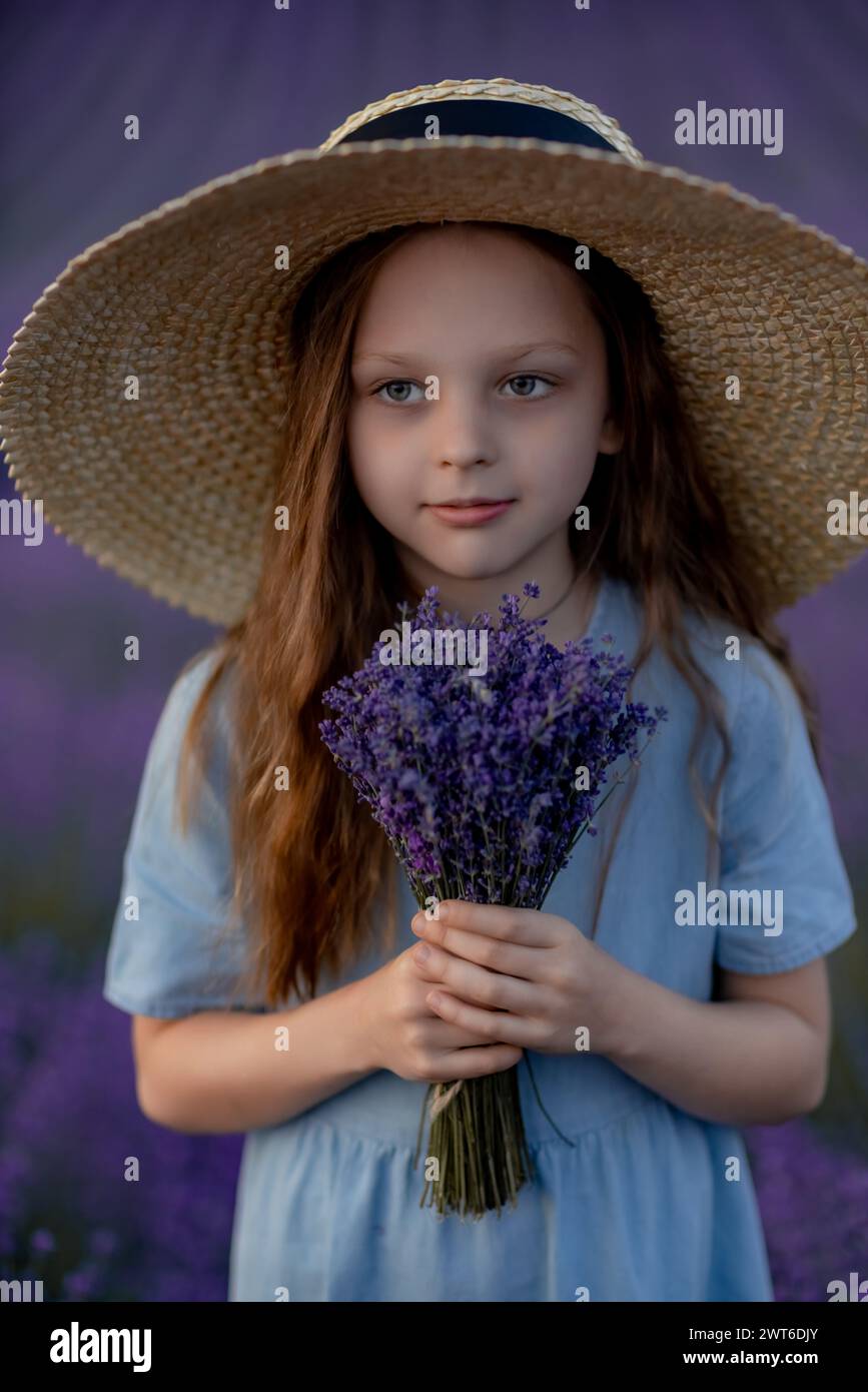 Girl lavender field in a blue dress with flowing hair in a hat stands ...