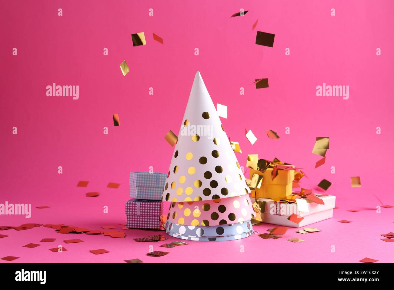 Party hats, gift boxes and confetti on pink background Stock Photo - Alamy
