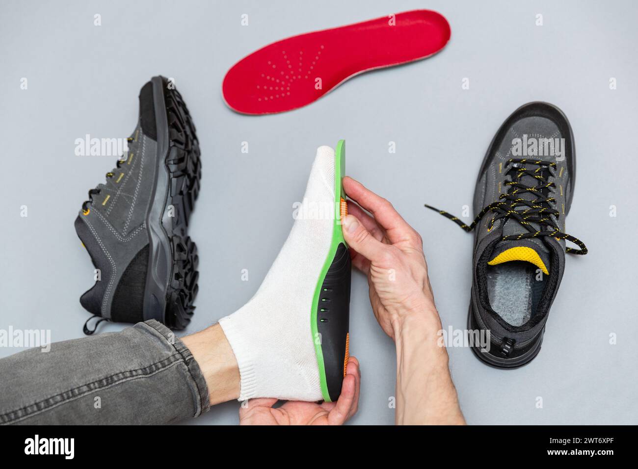 Close up of man hands fitting orthopedic insoles on a gray background. Healthcare and orthopedic treatment and prevention of flatfeet concept. Stock Photo