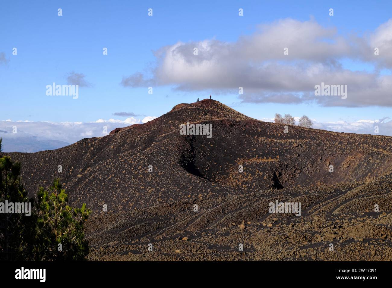 activities natural environment: silhouette of distant mountain bikers are exploring extinct volcano crater of 'Monte Nunziata' (1832) in Etna Park, S Stock Photo