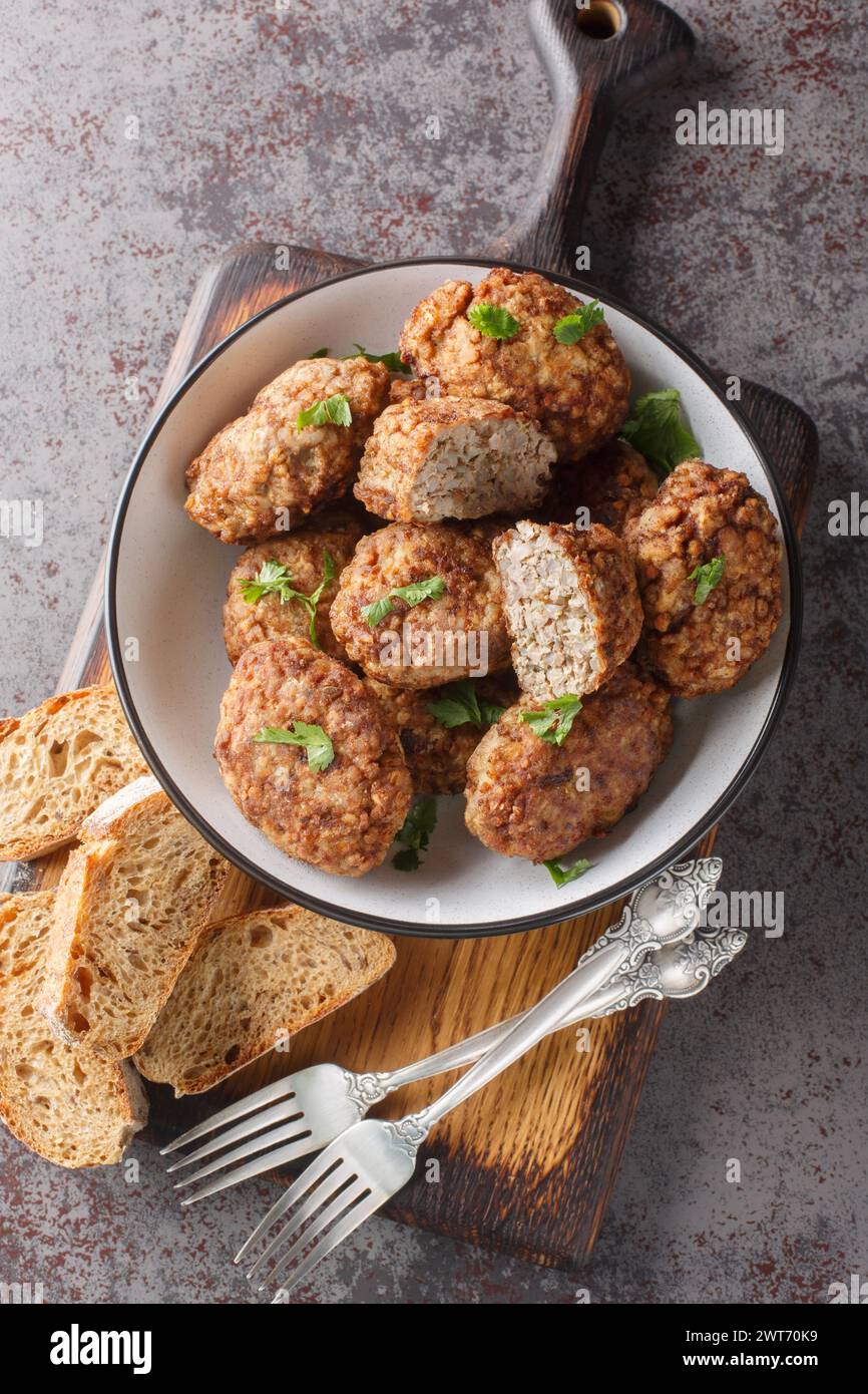 Buckwheat meatballs from minced meat and boiled buckwheat porridge with onions, spices close-up in a plate on the table. Vertical top view from above Stock Photo