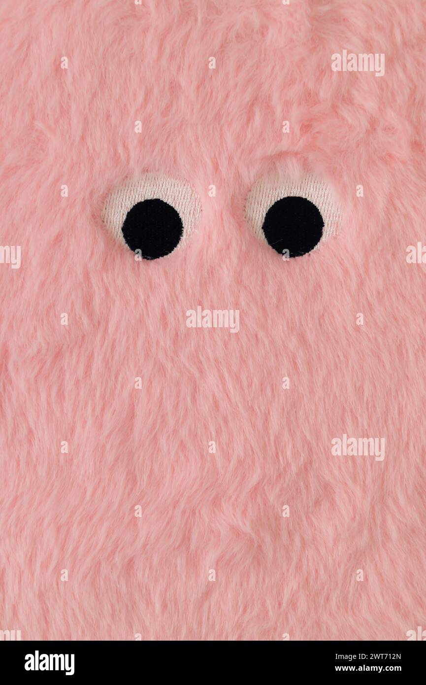 Cute fluffy monster made with pastel pink faux fur. Minimal concept. Creative funny face composition. An original peachy pink fur background image Stock Photo