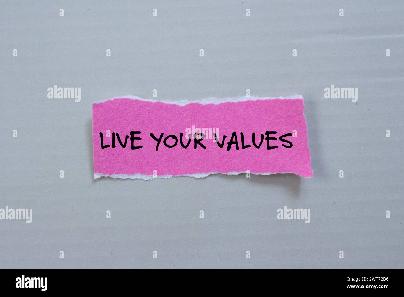 Live your values words written on pink torn paper piece with gray ...